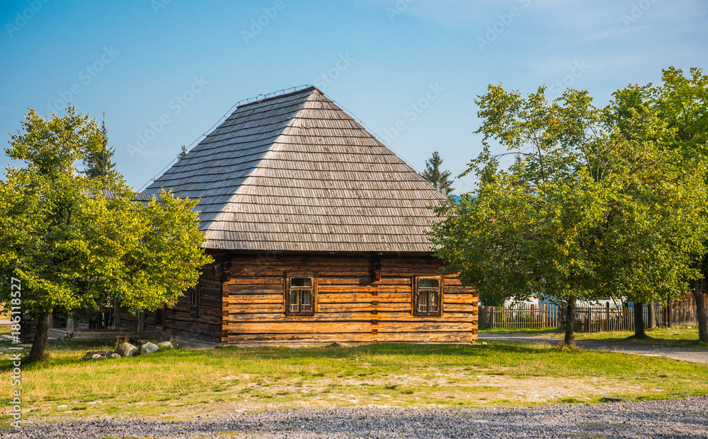 Obraz premium Old Wooden House with Trees on a Sunny Day