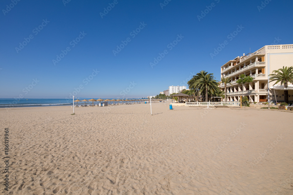 sandy and lonely Voramar Beach, in Benicassim, Castellon, Valencia, Spain, Europe. Buildings, blue clear sky and Mediterranean Sea. Horizontal
