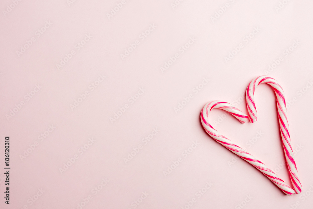 Minimal concept. Heart symbol made of christmas candies on pink background. Flat lay, top view, copy space