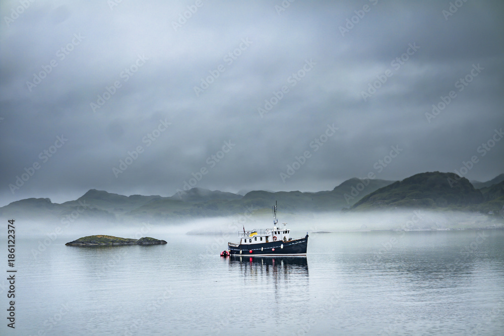 Alone boat driving through in the foggy sea in the scottish highlands