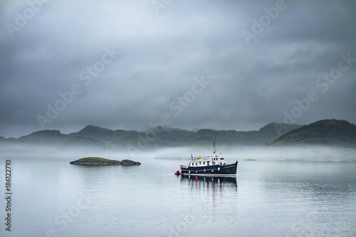 Alone boat driving through in the foggy sea in the scottish highlands photo