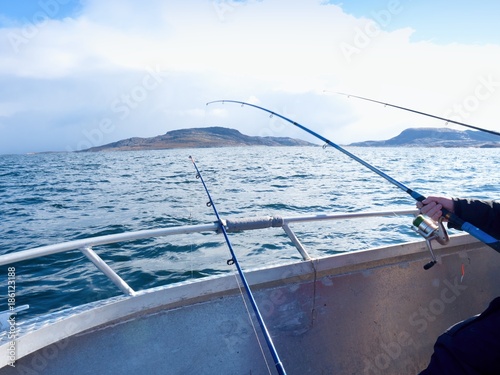 Fishing boat with fishing rods  floating in open sea. Background beautiful sky. Sport fishing photo