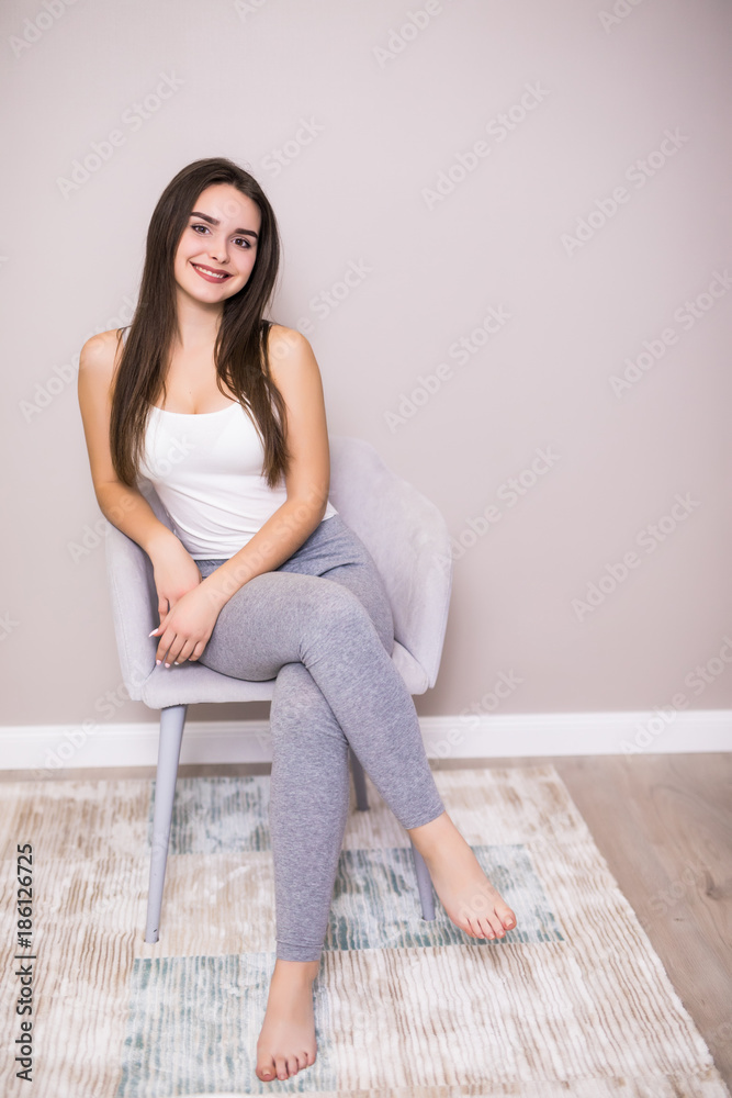 Young woman at home sitting on modern chair in front of window relaxing in her living room, stretching with closed eyes. Young woman at home sitting on modern chair in front of window relaxing in her living room, stretching with closed eyes.