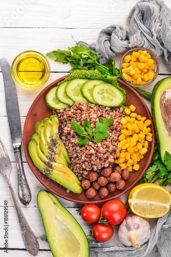 Healthy food. Buckwheat, avocado, cucumber, corn and hazelnut. On a wooden background. Top view. Free space for your text. © Yaruniv-Studio