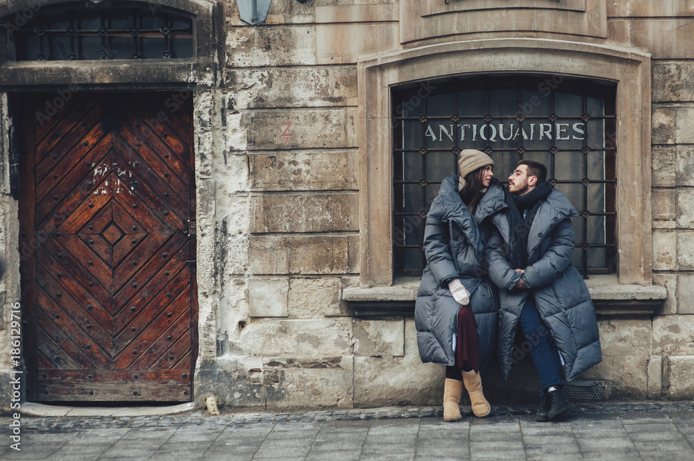 Classy groom and his gorgeous bride pose outside in winter coats