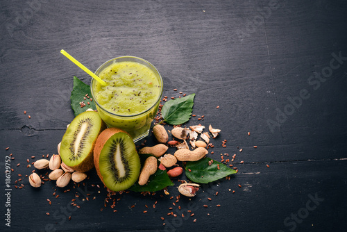 Kiwi smoothie with flaxseed and nuts. On a wooden background. Top view. Free space for your text.