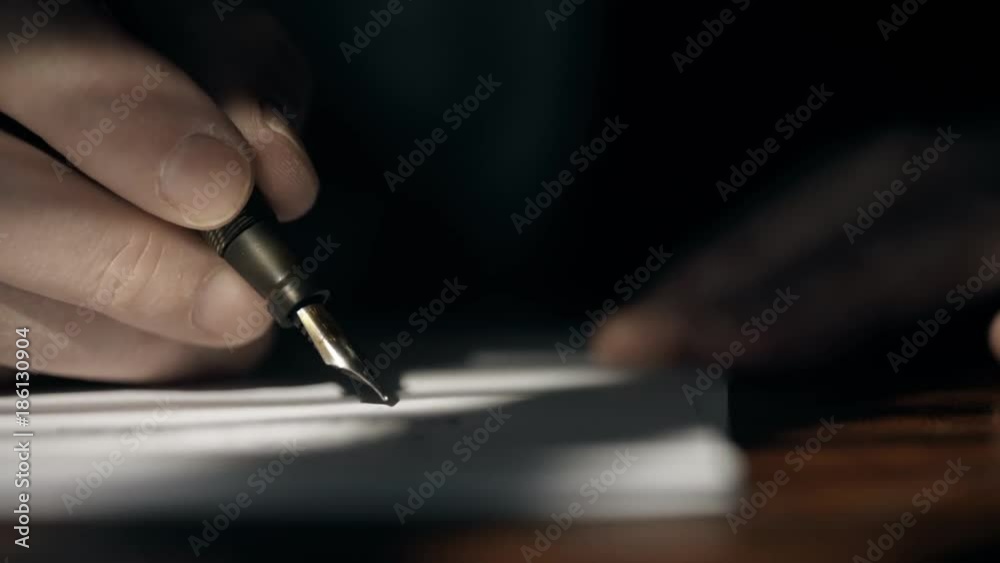 Super close footage of a Caucasian businessman in 1930 making entries into a business ledger or engaged in handwritten communication using a fountain pen.