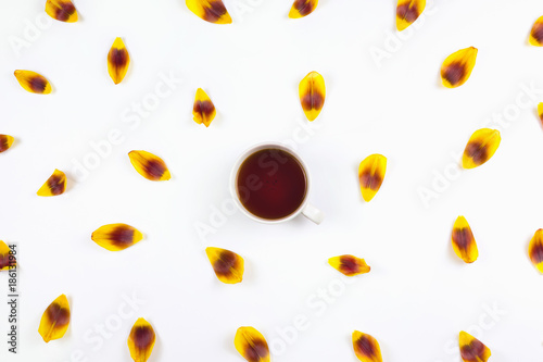 Flatlay with flower petals and cup of tea. Spring arrangement, white background