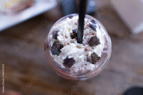 Cup of chocolate shake with whip cream on wooden table