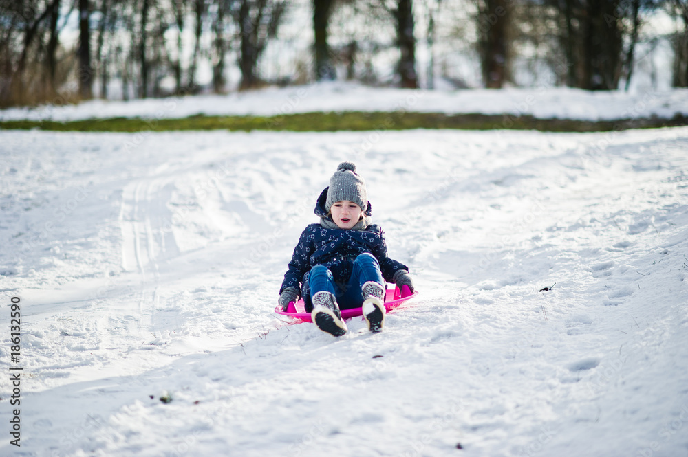 Cute little girl with saucer sleds outdoors on winter day.