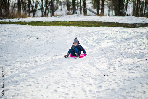 Cute little girl with saucer sleds outdoors on winter day.