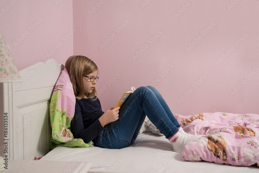 Obraz premium Mädchen liest auf ihrem Bett 