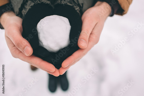 Happy Young Couple in Winter . Family Outdoors. man and woman looking upwards and laughing. Love, fun, season and people - walking in winter park. Snowball in the hands of close-up. photo