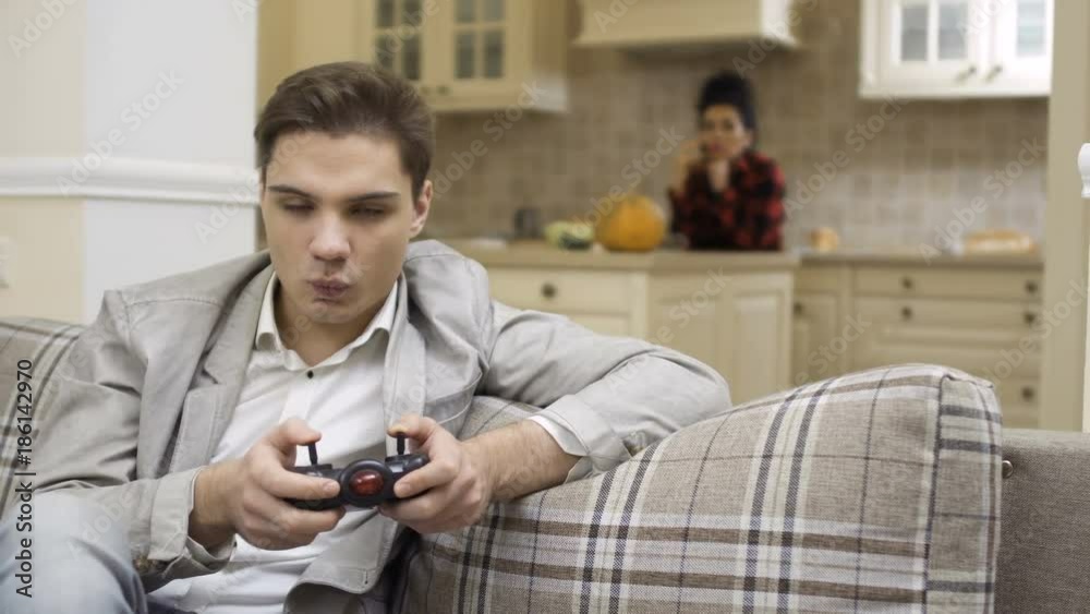 Young guy play video game and looks at camera Young guy play video game and looks at camera