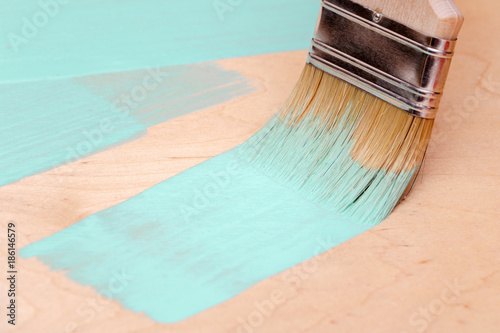 Staining the wooden surface of turquoise paint using a paint brush