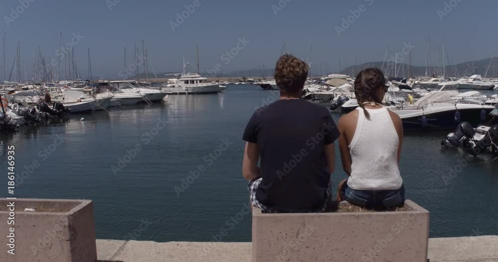 ALGHERO, SARDINIA, ITALY – JULY 2016 : Video shot of people enjoying view on a sunny day in Alghero harbor with boats in view ALGHERO, SARDINIA, ITALY – JULY 2016 : Video shot of people enjoying view on a sunny day in Alghero harbor with boats in view