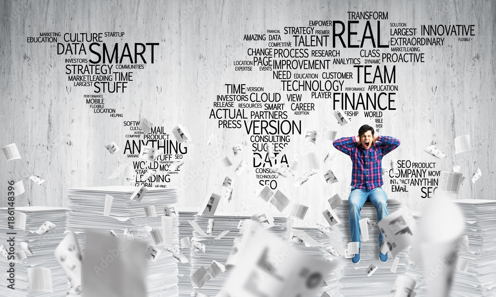 Attractive man sitting on pile of paper documents.