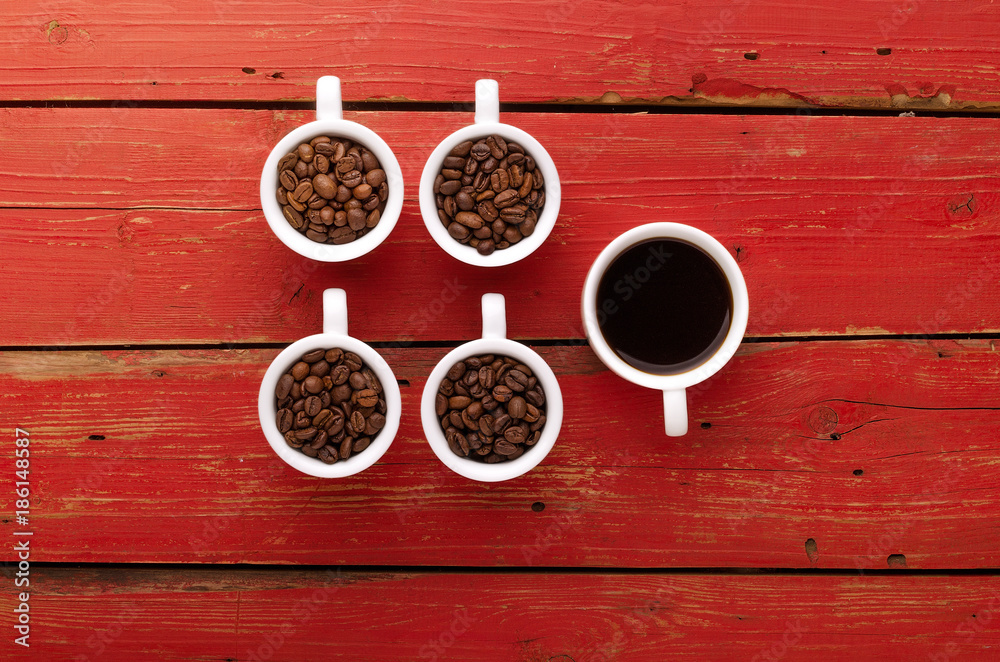 Coffee. Coffee cups and coffee beans on red wooden background.