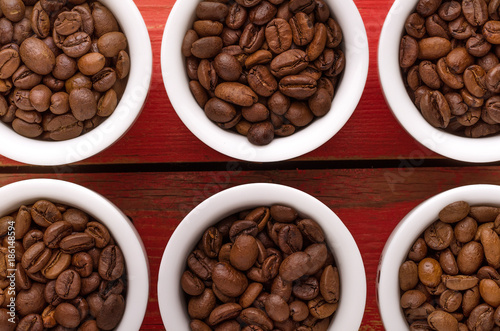 Coffee. Coffee cups and coffee beans on red wooden background.