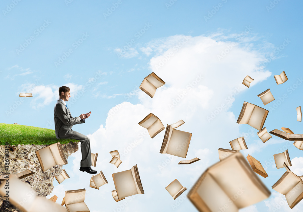 Man using smarphone and many books flying in air
