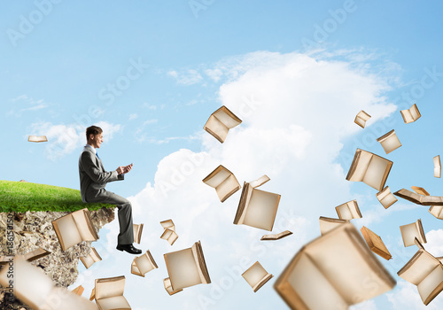 Obraz na płótnie Man using smarphone and many books flying in air w salonie
