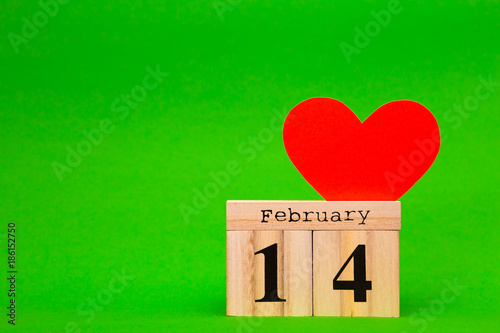 Happy Valentines Day card with red paper heart and wooden calendar on green background