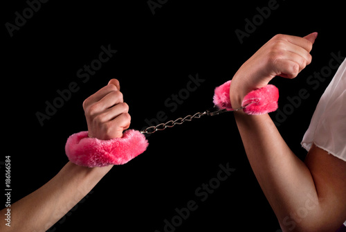 Two female hands tied with handcuffs. Close up