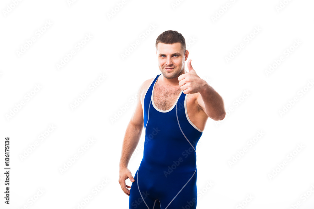 Young dark-haired man wrestling Greco-Rican wrestling, master of sports in grappling in blue wrestling tights smiling and holding his thumb up against white isolated background Young dark-haired man wrestling Greco-Rican wrestling, master of sports in grappling in blue wrestling tights smiling and holding his thumb up against white isolated background