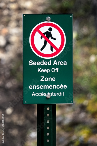 A seeded area keep off sign in french and english