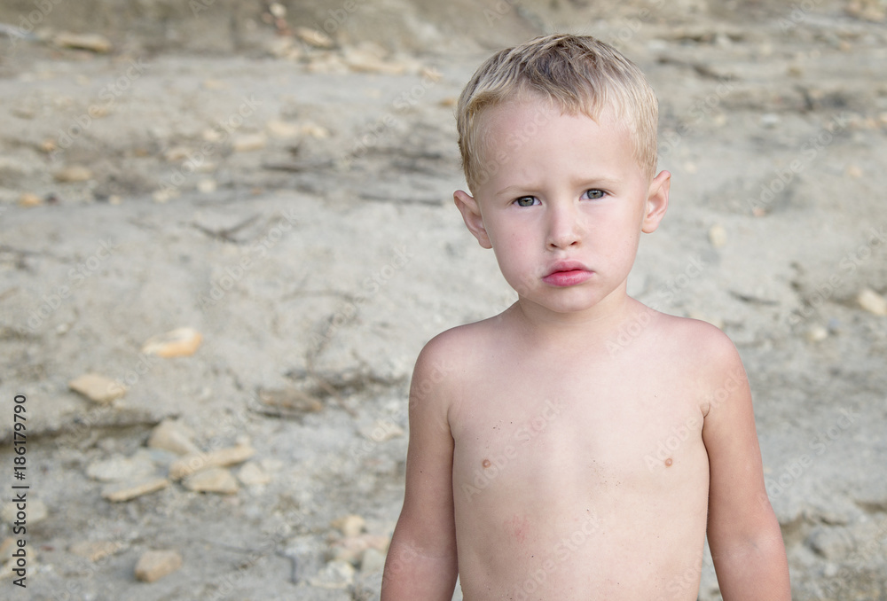 Sweet, serious little, blonde boy, shirtless at the beach in summer Sweet, serious little, blonde boy, shirtless at the beach in summer