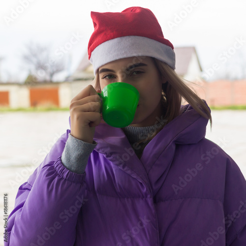 Pretty young girl drinks coffee or tea, street  