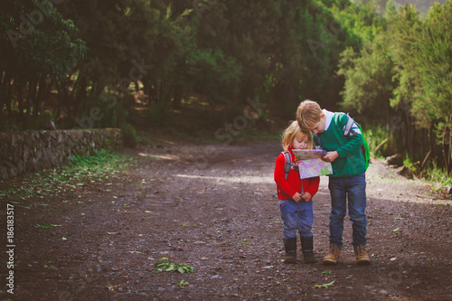 little boy and girl travel hiking in nature looking at map