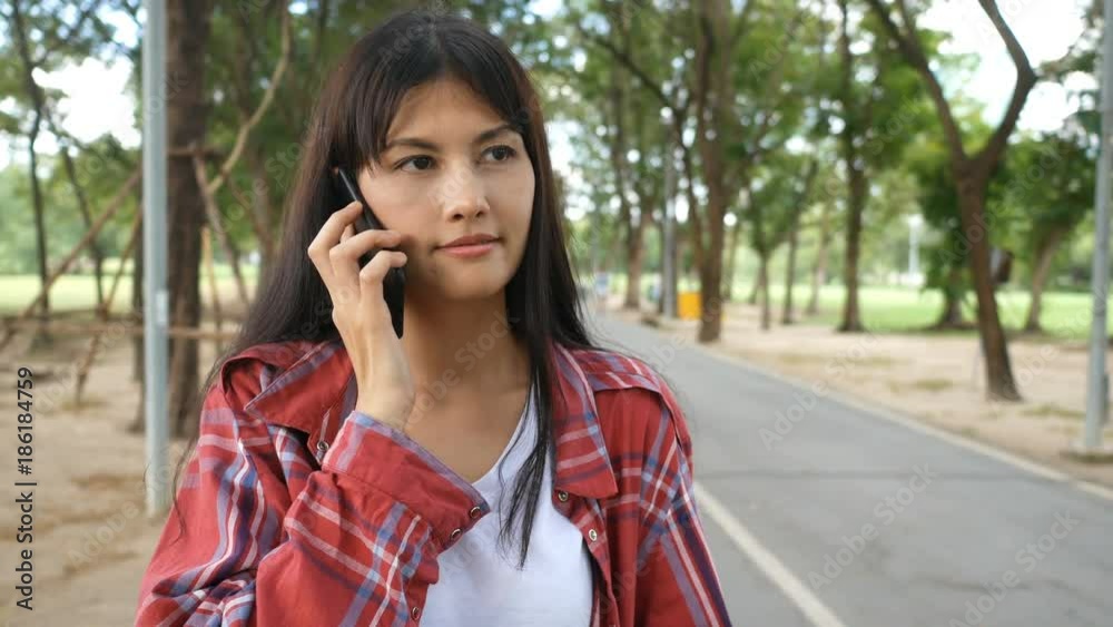 Asian woman using smartphone for talk at park. Asian woman using smartphone for talk at park.