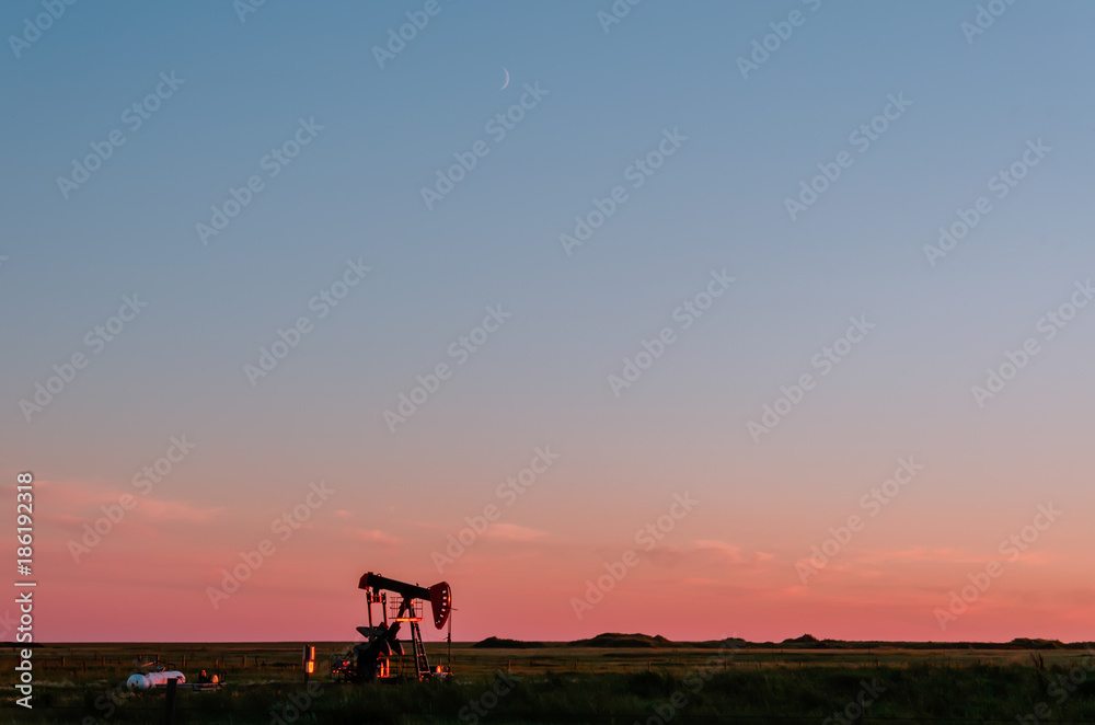 Fototapeta premium At sunset, oil pumps pump oil on a black field.