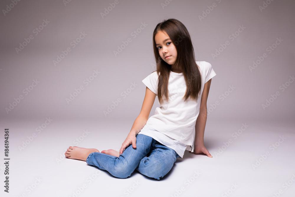 Adorable smiling little girl sitting on a floor isolated on a white background