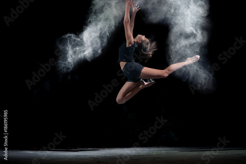 Dancing girl in a jump with dust powder