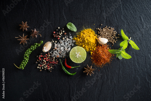 Flat-lay of spices and herbs on black background. Ingredients for cooking. Food background on stone. Top view copy space