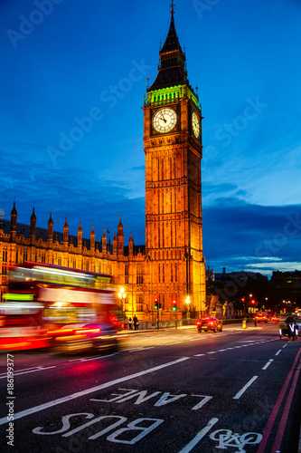 London night traffic scene with Double Decker bus moves along illuminated Elizabeth Tower aka Big Ben on the Westminster Bridge