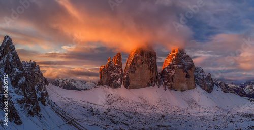 Colorful sunset sunset in Dolomites mountains, three peaks of Tre Cime di Lavaredo in snowy and cloudy background. Italy, Europe. photo
