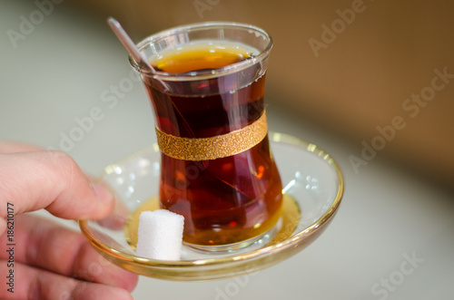 Close-up of delicious red Turkish tea with traditional pear shaped glass with a teaspoon in the man hand photo