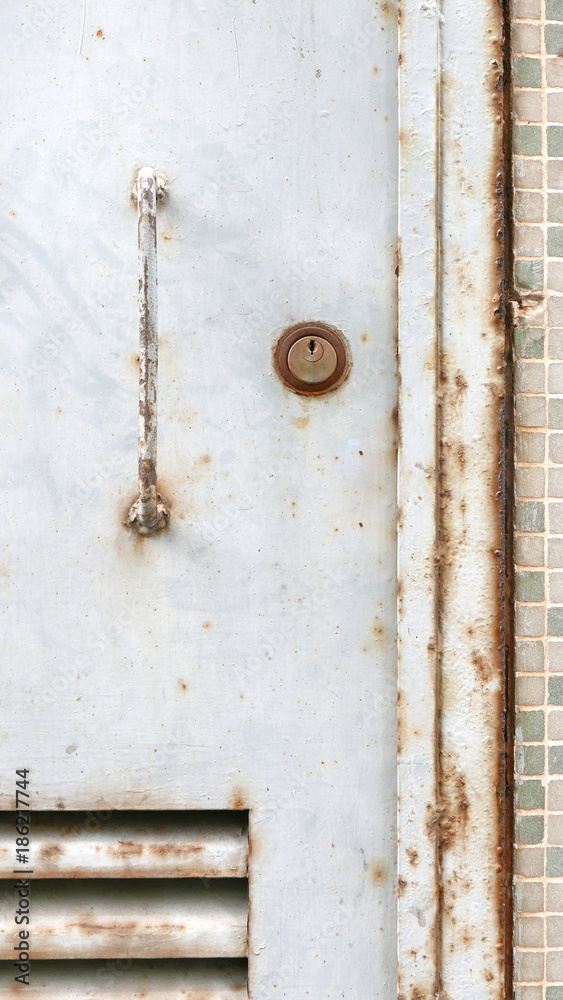The grunge metal door close-up with handle and key lock The grunge metal door close-up with handle and key lock
