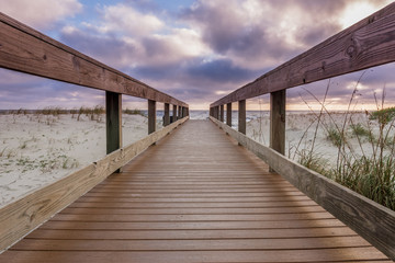Fototapete Abstieg zum Strand Morgenwolken über hölzernem Strandsteg  © kellyvandellen