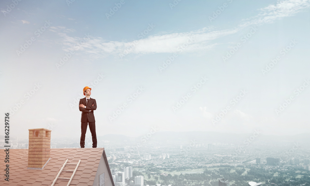 Engineer man standing on roof and looking away. Mixed media Engineer man standing on roof and looking away. Mixed media