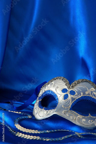 Image of elegant venetian mask over blue silk background.