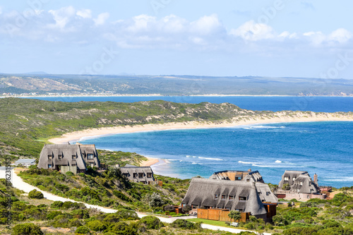 Beautiful view of Bosbokduin Private Nature Reserve in Still Bay, South Africa. It is known for its thatched roofed houses.  Skulpiesbaai Local Nature Reserve with a beautiful beach in the background. photo