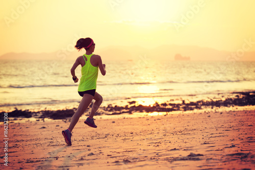 Full length of silhouette young woman jogging on shore. Side view of asian female is running during sunrise © lzf