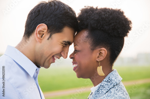 Side view of young romantic smiling couple who standing face to face outdoors