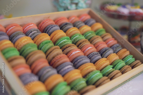 Large wooden display of colorful macarons at a candy bar at a reception  wedding or a party
