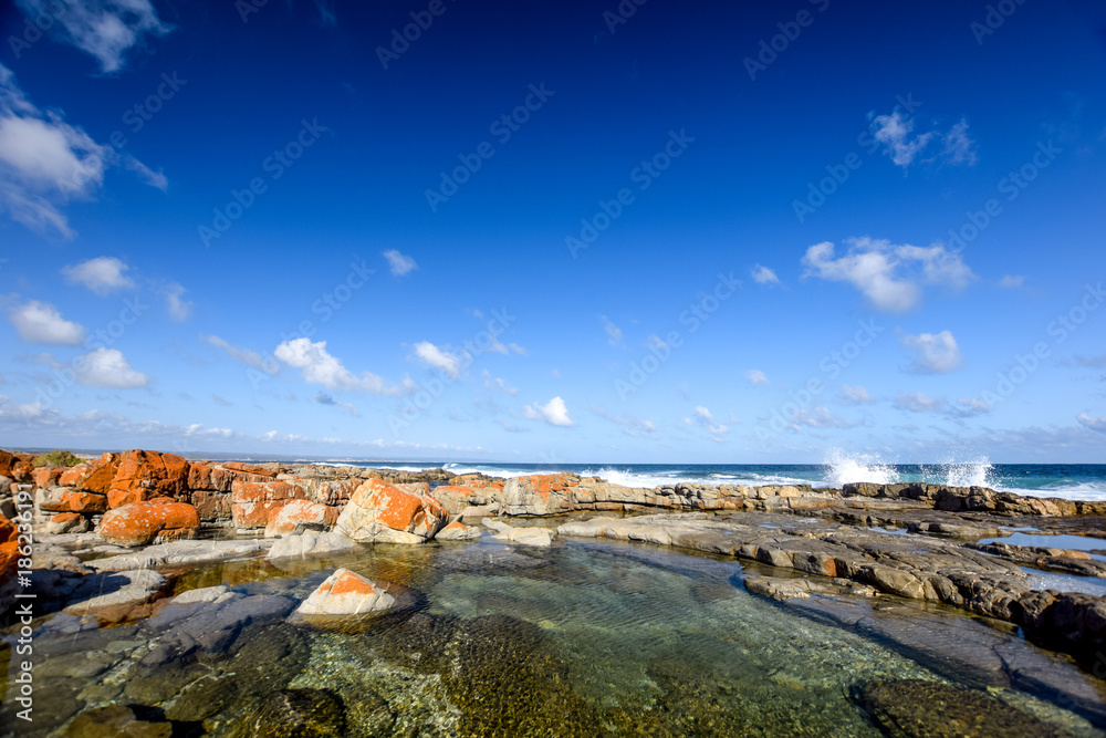 Beautiful view of rock pools at the Bosbokduin Nature Reserve in Still Bay, Western Cape Province, South Africa. Ocean waves breaking in the background.