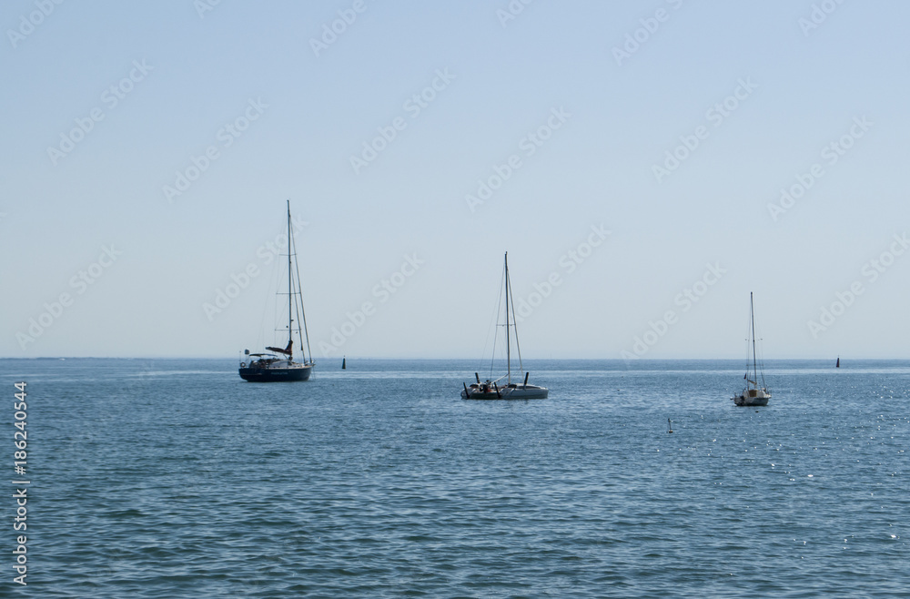 Hot midday on the Black Sea. Three sailing boats on the surface of calm sea.